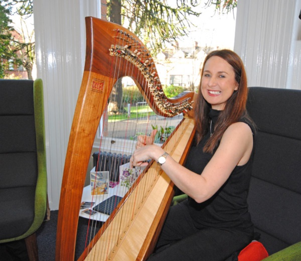 Sharon plying harp and smiling